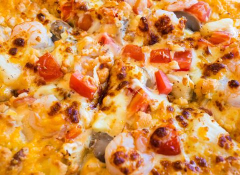 Fresh pizza with tomatoes, cheese and shrimp on wooden table close up.