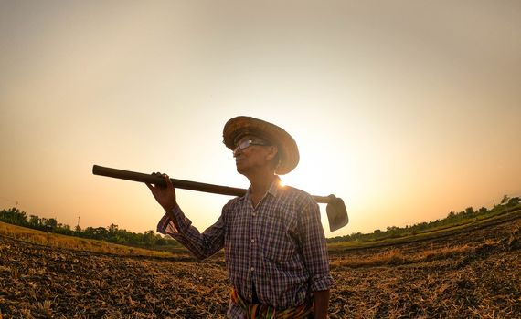 Elderly Asian farmers shoveling and prepare the soil with a spade for planting on sunset background.