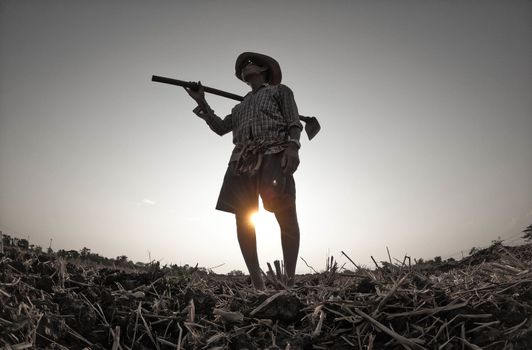 Elderly Asian farmers shoveling and prepare the soil with a spade for planting on sunset background.