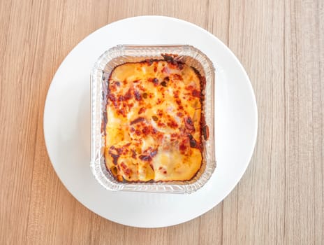 Macaroni with ham and cheese in a baking dish on wooden table. Top view.