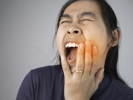 Woman catching on cheek because she have a toothache. Healthcare and medical concepts.