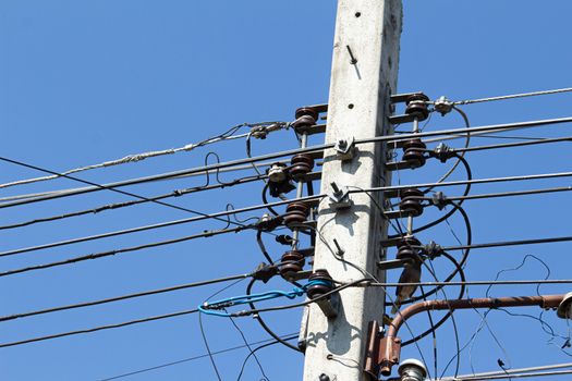 Messy electrical cables and wires on electric pole on clear blue sky background.