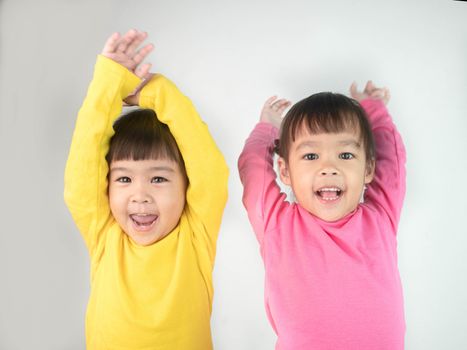 Portrait of a happy smiling brethren girls and hand raised isolated on grey background.