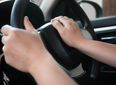 Close up inside vehicle of female hand pushing on steering wheel and honking with angry. Technology and transportation concepts.