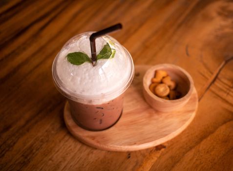 Ice chocolate or cocoa milk served with biscuits on wooden table, top view.
