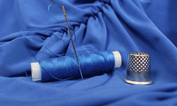Blue Thread with needle and thimble on blue prom dress