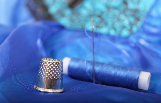 Blue Thread with needle and thimble on blue prom dress