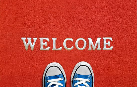 red welcome carpet with blue sneakers on it. welcome sign concept