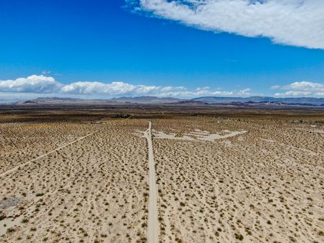 Aerial view of endless desert straight dusty asphalt road in Joshua Tree Park. USA. Long straight tarmac road heading into the desert to the direction of Arizona.