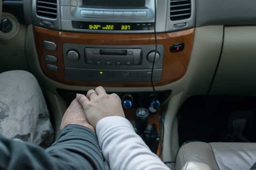 touching the hands of men and women, on the background of controls, receiver and car panel