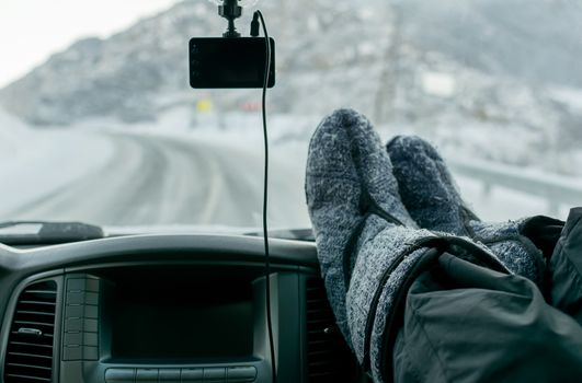 Foot passenger on the car panels in the warm boots, and winter mountain roads