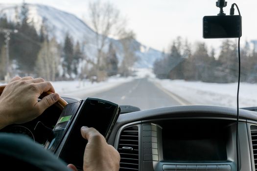 Caucasian man talking on the phone while driving a car on a slippery snow covered road in the taiga