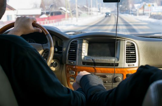 touch of hands of the man and the woman, against controls, the monitor, the panel of the car and the carriageway covered with snow in the settlement behind a window