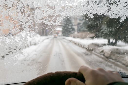 view of the fogged icy cold windshield of the car from the driver's side of the car