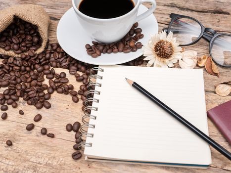 hot coffee cup with coffee bean and notebook with pencil on wooden table. coffee background menu for cafe or coffee shop