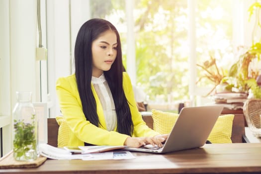 young beautiful Asian businesswoman sitting at table in coffee shop working with laptop