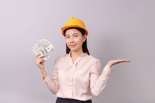 loans for real estate concept, woman with yellow helmet holding banknote money in right hand and open the empty palm of the left hand