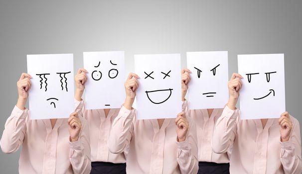 five businesswoman holding a card with drawing facial expressions different emotion feelings face on white paper