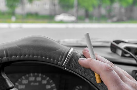 close-up, the hand of the driver of the car holds a cigarette