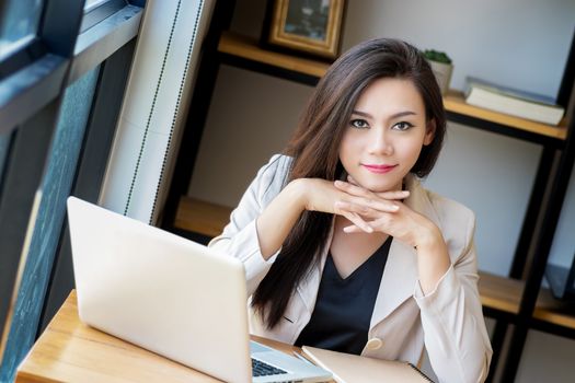 portrait of beautiful and confident Asian business woman in working age using computer laptop technology for manage job work, look at camera. businesswoman ,  girl power concept