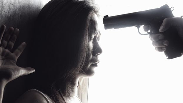 man use handgun aim on women's heads for intimidate. stop domestic violence against women campaign. reform gun control concept