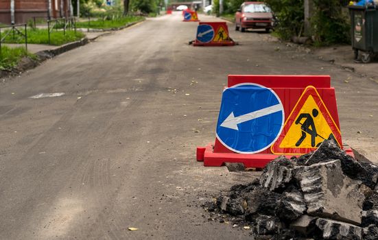 road sign, detour, road repair on the background of the road and broken asphalt pieces on the urban street