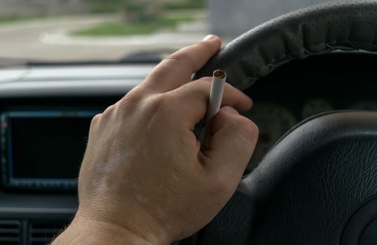 close-up, the hand of the driver of the car with skin disease "vitiligo" holds a cigarette