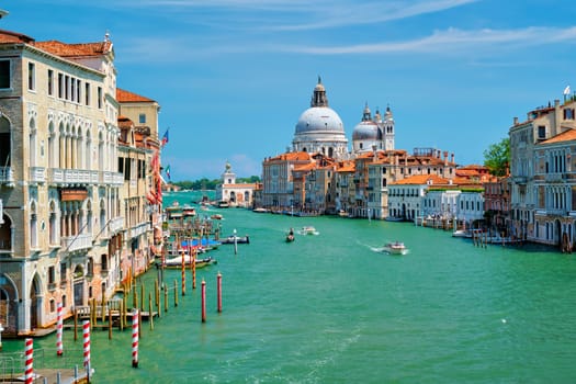 View of Venice Grand Canal with boats and Santa Maria della Salute church in the day from Ponte dell'Accademia bridge. Venice, Italy