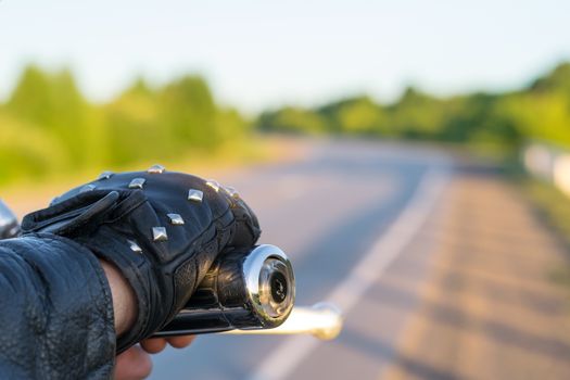 closeup of the hand of the biker on the control handle of the motorcycle and the view of the road