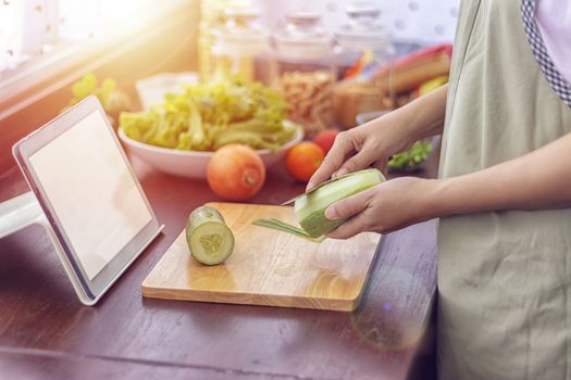 female hand slicing green vegetable, prepare ingredients for cooking follow cooking online video clip on website via tablet. cooking content on internet technology for modern lifestyle concept