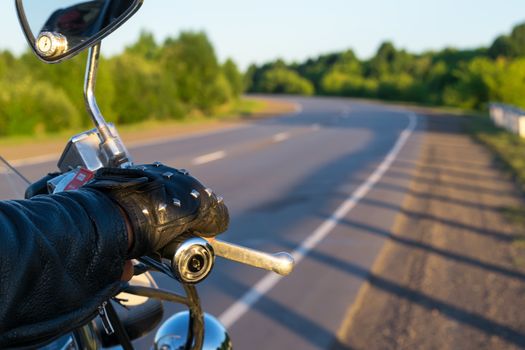 closeup of the hand of the biker on the control handle of the motorcycle and the view of the road