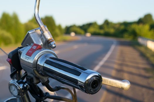 view of handlebar grips of the motorcycle on the country road background closeup