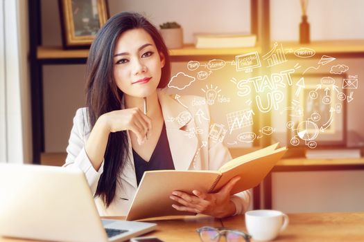 portrait of beautiful and confident Asian business woman in working with notebook laptop and book manage job work at workplace with startup business plan in foreground