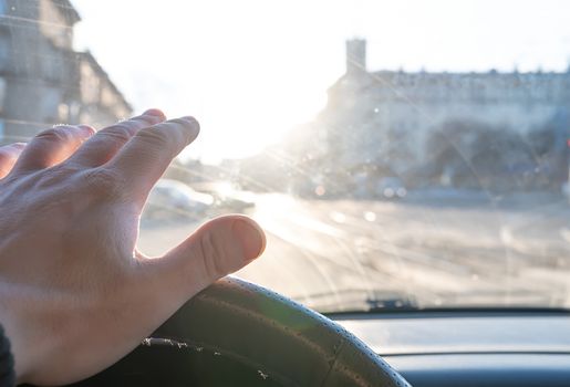 The hand of the driver of the car covers the sunlight, which blinds the person to see the road situation