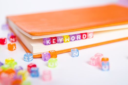 KEYWORDS word on colorful bead block as bookmark in book. keywords research and content marketing idea concept