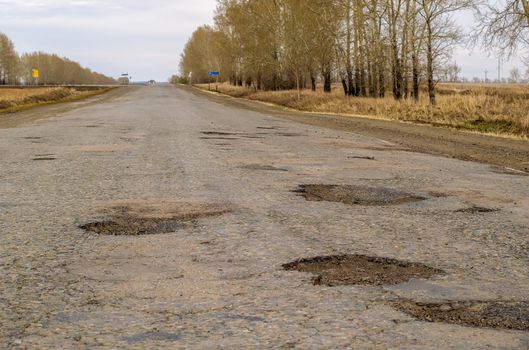 Pits on a country road. Damaged asphalt on the track