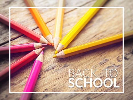 colorful color pencils on old wooden table with text back to school