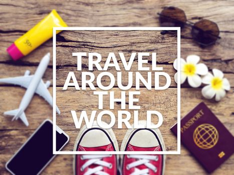 flat lay of passport , mobile , plane model , red sneakers and traveler's accessories items on wooden background with text travel around the world. travel and vacation concept