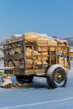 Cart, trailer, wagon for transportation of firewood is for sale in the countryside in the snow in winter