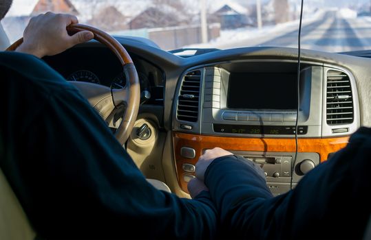 touch of hands of the man and the woman, against controls, the monitor, the panel of the car and the carriageway covered with snow in the settlement behind a window