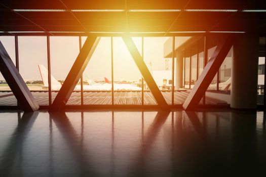 view of airplane parking at the gate from walk way bridge between terminal at the airport with light effect, background for travel and vacation concept