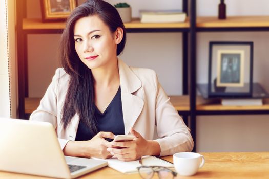 portrait of beautiful and confident Asian business woman in working age using computer laptop technology and smartphone for manage job work at work space. businesswoman and girl power concept