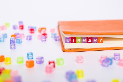 LIBRARY word on colorful bead block as bookmark in book. knowledge from book resource in library concept