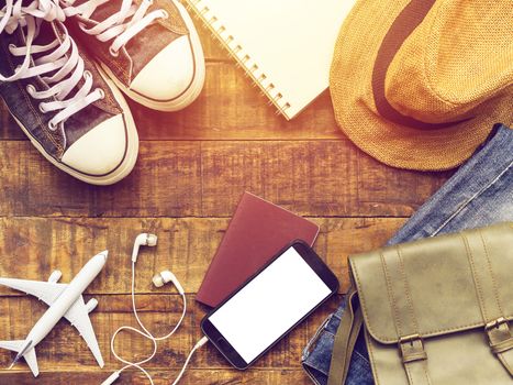 flat lay of passport ,mobile, plane model , sneakers , wallet , camera and traveler's accessories items on wooden background with copy space. travel and vacation concept