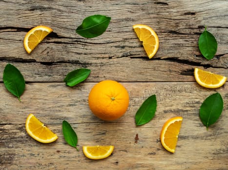 composition of slices, whole of orange fruits with green leaves on wooden background. top view