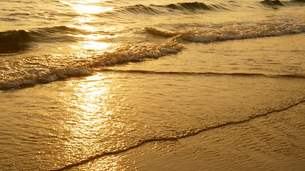 amazing sunset over the tropical beach. ocean beach waves on beach at sunset time , sunlight reflect on water surface. beautiful evening nature sea background.