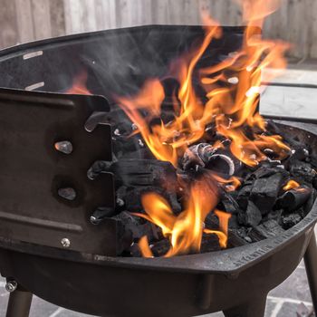 The flames lick the coal, while preparing the barbecue.