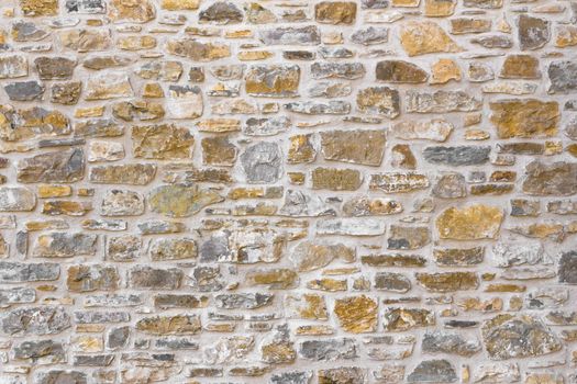 Old irregular golden stone wall, background.