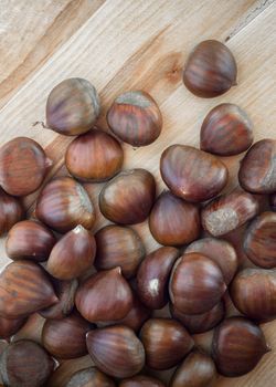 Chestnuts scattered on a wooden table, seen from above