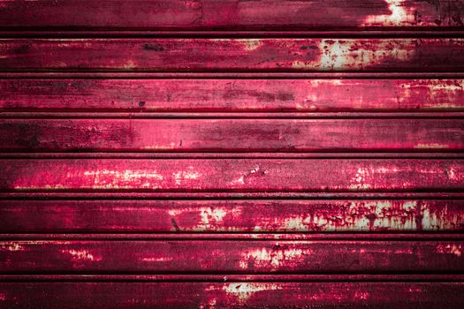 Front view of a shutter rusted pink, deteriorated from elements.